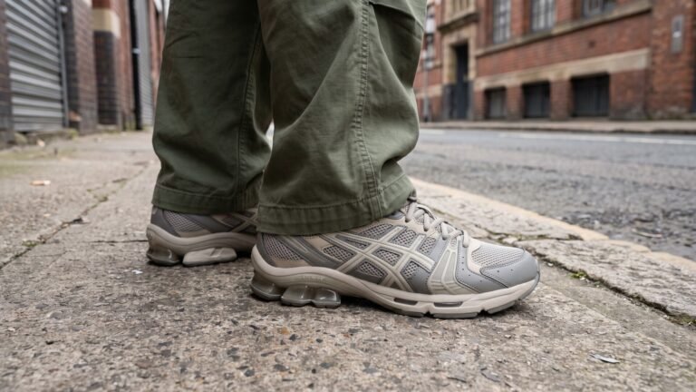 Side profile of ASICS GEL-Kinetic Fluent sneakers worn with olive cargo pants on an urban street sidewalk