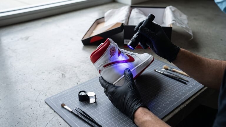 Sneaker authenticator in black gloves inspecting an Air Jordan shoe with a UV blacklight flashlight