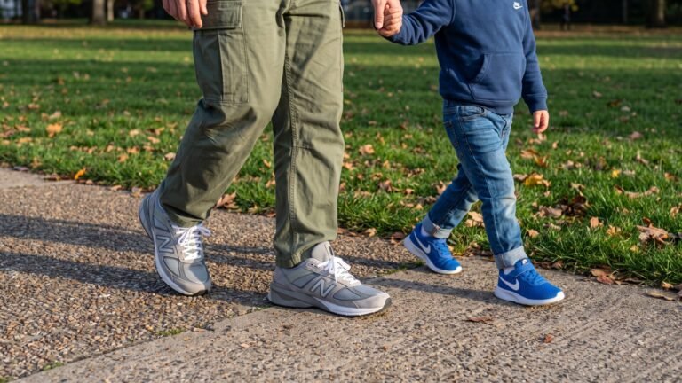 Adult and child in supportive sneakers walking hand-in-hand along a paved park path