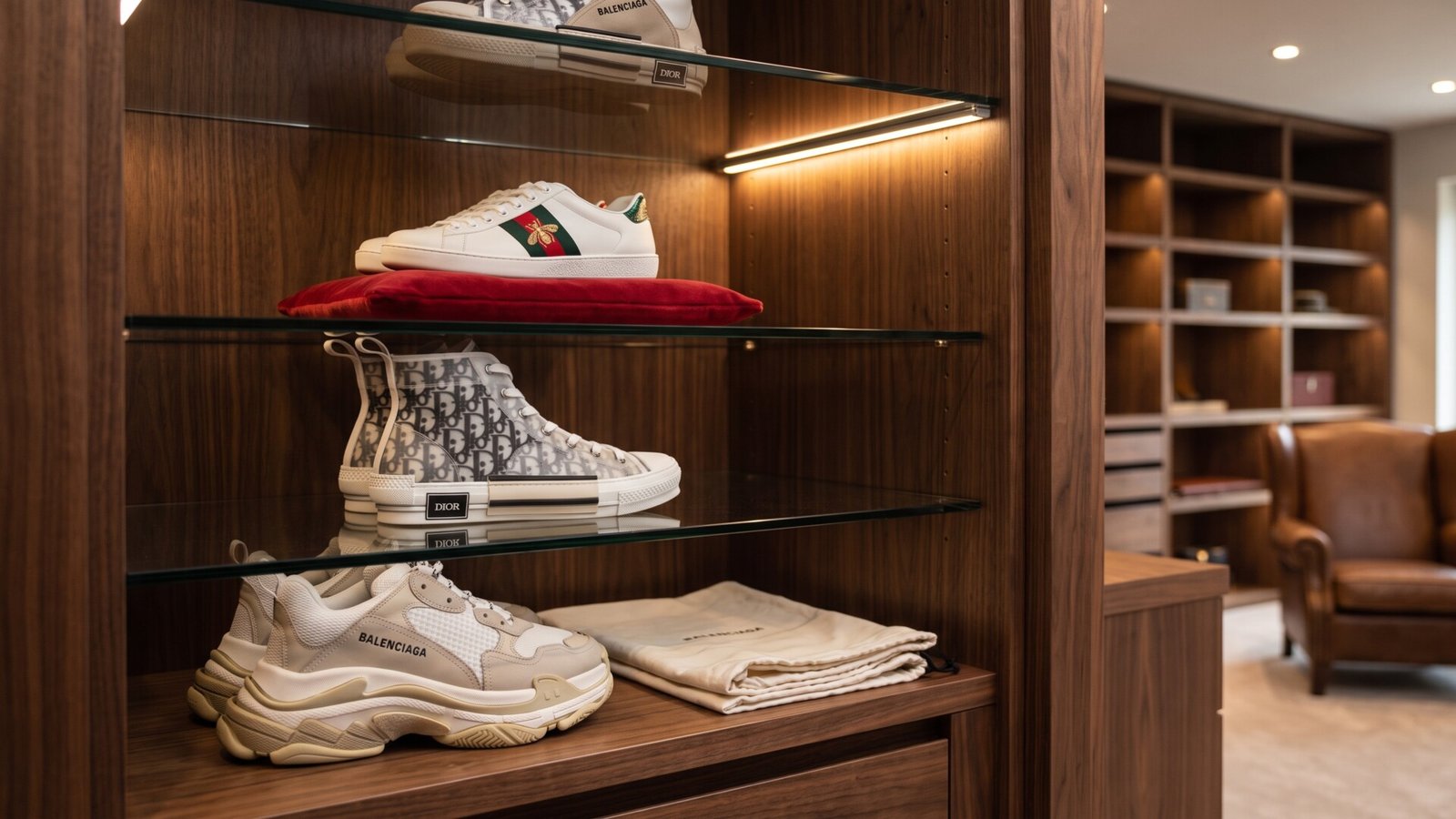 Gucci Ace, Dior B23, and Balenciaga Triple S sneakers displayed on illuminated wooden closet shelves