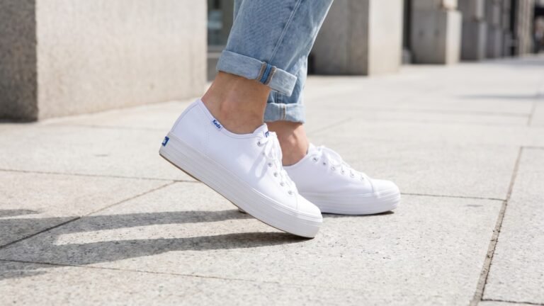 White canvas Keds Triple Kick platform sneakers styled with cuffed light-wash jeans on a sidewalk