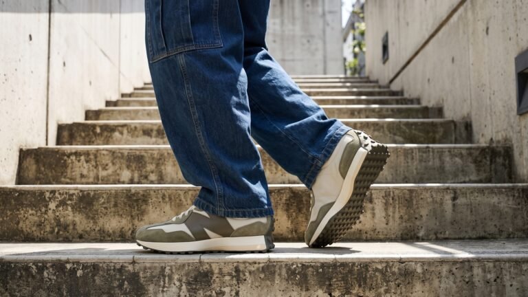 New Balance 327 sneakers in olive green and cream styled with blue jeans on concrete stairs