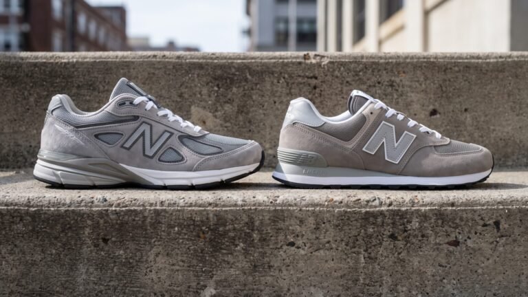 Side-by-side profile view of a grey New Balance 990 and a grey 574 sneaker resting on concrete