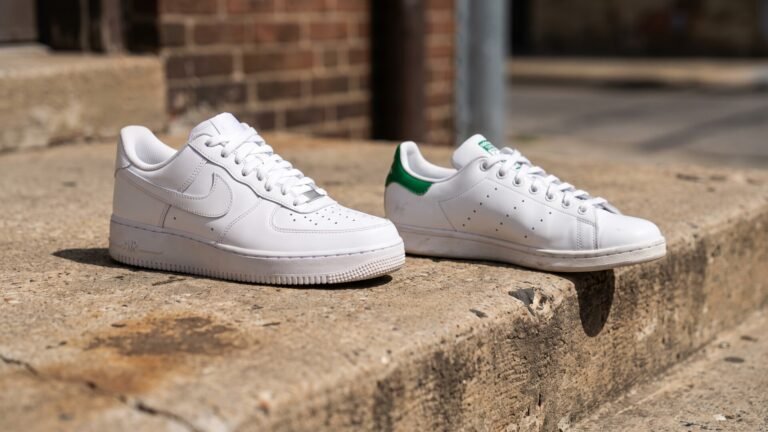 Nike Air Force 1 Low and Adidas Stan Smith sneakers displayed side by side on a concrete step