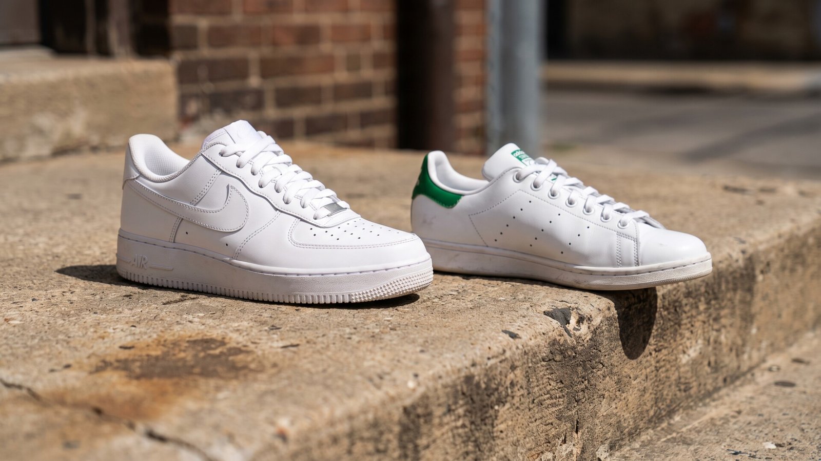 Nike Air Force 1 Low and Adidas Stan Smith sneakers displayed side by side on a concrete step