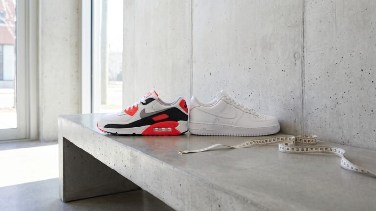 Nike Air Max 90 and all-white Air Force 1 sneakers side by side with a measuring tape on a concrete bench