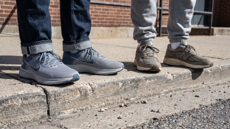 Two people standing on a concrete curb wearing grey Nike running shoes and tan New Balance sneakers
