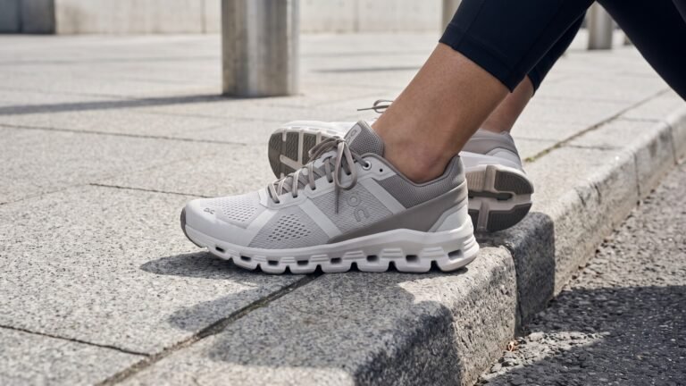 Close-up of grey and white On Cloudrunner running shoes resting on a concrete city curb
