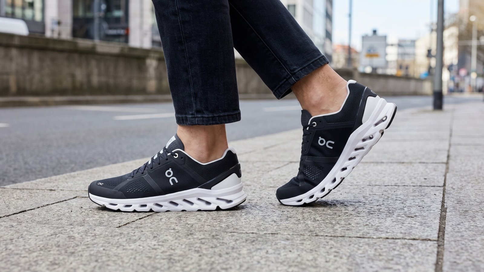 Black and white On Cloudsurfer running shoes worn while stepping along a paved city sidewalk