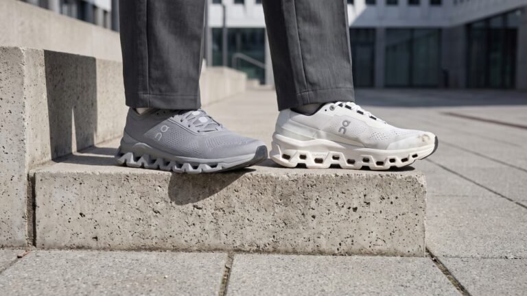 Person wearing an On Cloudtilt on one foot and a Cloudmonster on the other while standing on concrete steps