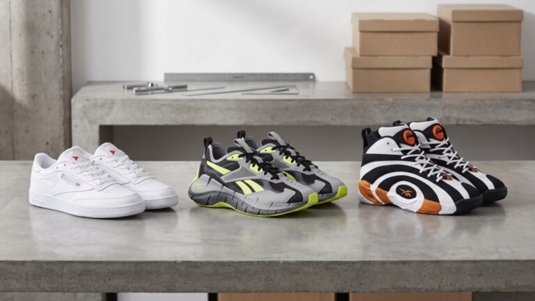 Three pairs of heritage and modern Reebok sneakers lined up on a concrete workbench