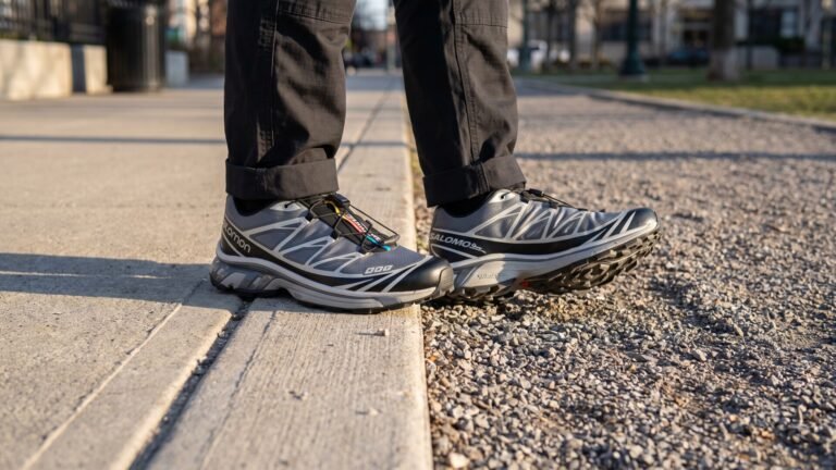 Person wearing grey and black Salomon XT-6 sneakers stepping from a concrete curb onto gravel