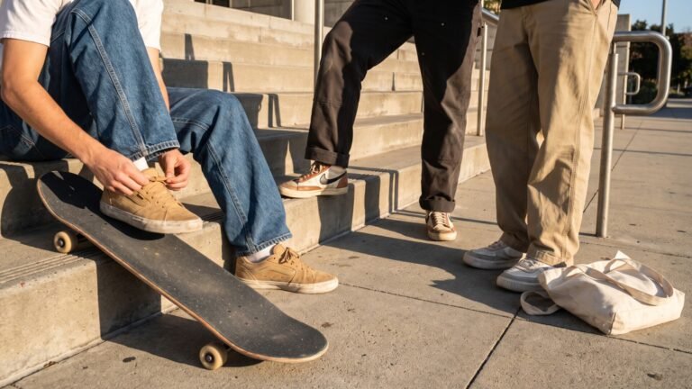 Three skaters wearing trendy sneakers and casual streetwear standing on concrete steps with a skateboard