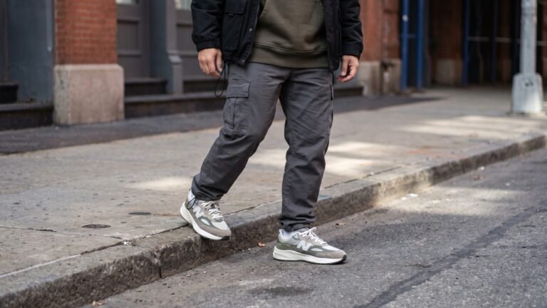Person wearing grey cargo trousers and neutral athletic sneakers stepping off a city sidewalk curb