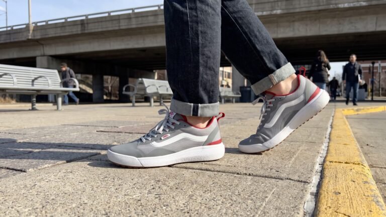 Person wearing grey and red Vans UltraRange sneakers mid-stride across an urban transit plaza